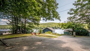 A campground with a paved parking area, several cabins, and a lake in the background.