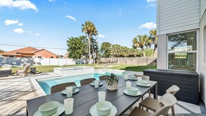 A backyard with a pool, dining table set with plates and cups, and a potted plant. - Designer Home - 9 Beds - New Pool - By Beach (Cocoa Beach)