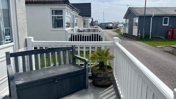 A residential street with houses, a bench, and a potted plant on a porch. - SeasideEscape-2Br-Sleeps4-Parking-PetsOK-Fireplace (Bridlington)
