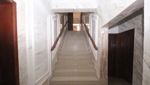 Un escalier en marbre, doté de rampes en bois, mène à une porte en bois sombre située en haut.
