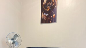 Ein modernes Wohnzimmer mit einem dunkelblauen Sofa, einem weißen Couchtisch und einem Standventilator.