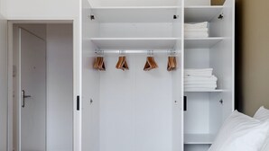 Une chambre d’hôtel moderne, dotée d’une grande armoire, d’un lit et d’une literie soigneusement préparée.
