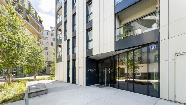 A modern building with a glass entrance and a sign that reads "See See Towers."