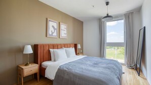 A bedroom with a bed, bedside tables, a lamp, a TV, and a window with curtains.