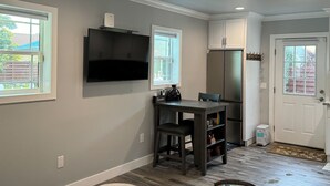 A modern kitchen with a built-in TV, a refrigerator, and a dining area with a table and chairs. - The Tiny cottage in quite charming. Palos Verdes with AC, WiFi and washer/dryer  (Rancho Palos Verdes)