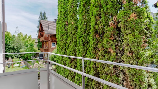 A balcony with a metal railing overlooking a garden and a wooden house. - Gorgeous Horgen 3BR, 2 min to Train Station, by Blueground (Zurich)