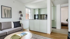 A modern apartment with a grey sofa, a round coffee table, and a kitchen area with green cabinets. - Gorgeous Horgen 3BR, 2 min to Train Station, by Blueground (Zurich)