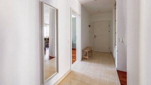 A hallway with white walls, a wooden bench, and a door at the end.