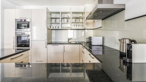 A modern kitchen with built-in appliances, a central island, and a stainless steel range hood.