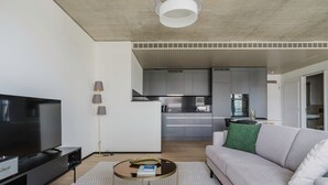 Un salon moderne avec un téléviseur à écran plat, un canapé, une table basse et un lampadaire.