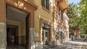A building with a bar and restaurant sign, large wooden doors, and a sidewalk. - GuestHost - Piazza Nievo in Trastevere Cozy Apartment (Roma)