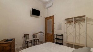 A bedroom with a bed, a wooden dresser, a chair, a TV, a wardrobe, and a radiator. - GuestHost - Piazza Nievo in Trastevere Cozy Apartment (Roma)