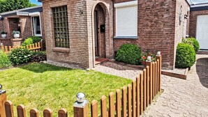 Ein modernes Ziegelhaus mit gepflegtem Rasen, Holzzaun und kleinem Garten.