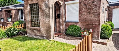 Una casa moderna de ladrillo con un césped cuidado, una valla de madera y un pequeño jardín.