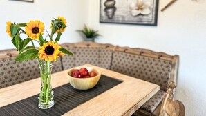 Ein Esstisch mit einer Sonnenblumenvase, einer Schale mit Kirschen und einer Holzskulptur.
