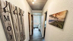 Ein Flur mit Holzdruck, einem Gemälde und Blick in einen Raum mit einem Fenster.