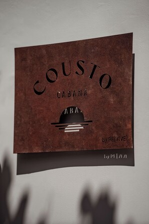 Biglietto da visita per 'COUSTO CABANA' con un design minimalista e un logo che presenta una montagna e un sole stilizzati.