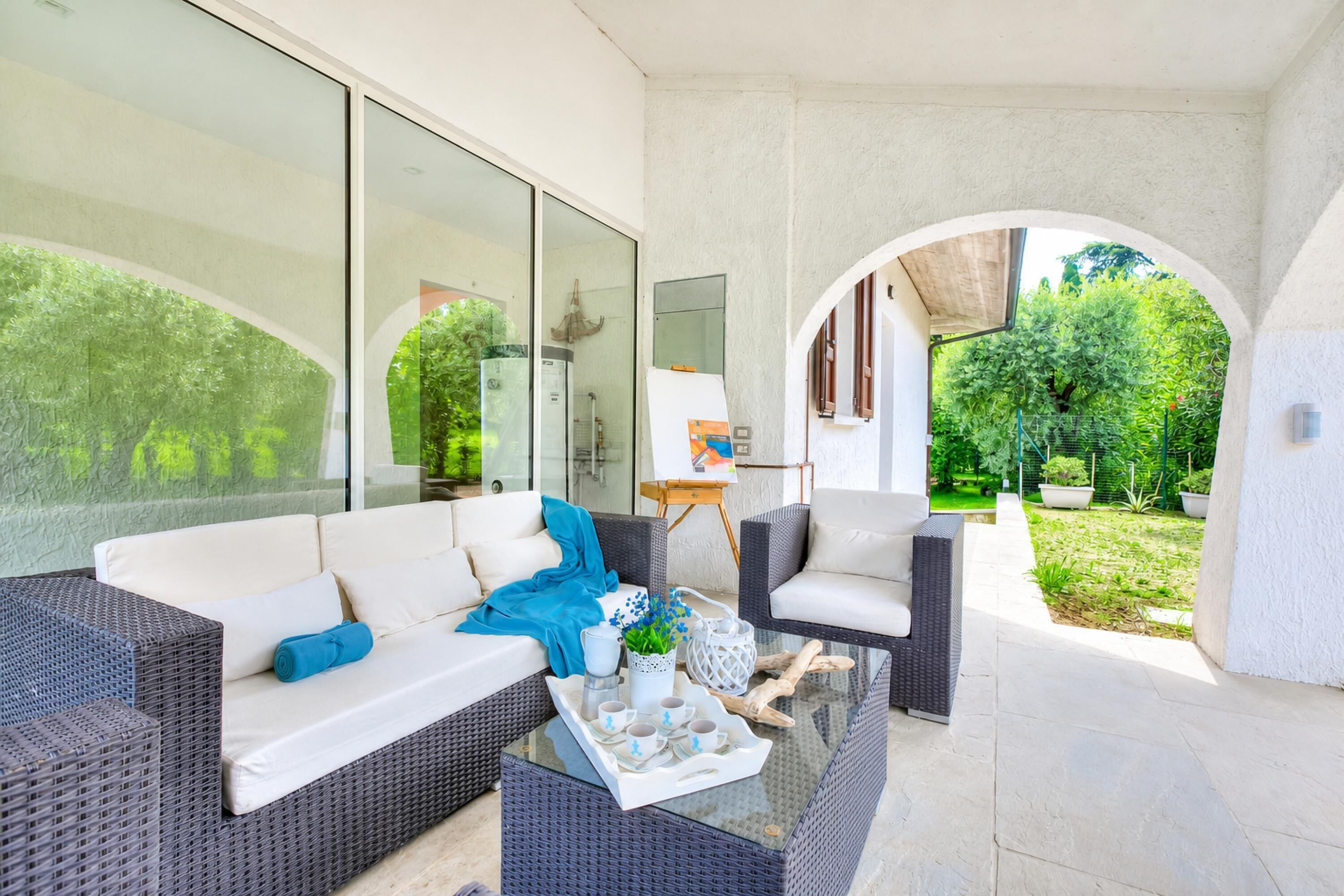 A modern outdoor living space with a sofa, chairs, and a glass coffee table.