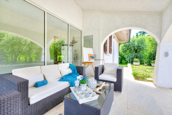 A modern outdoor living space with a sofa, chairs, and a glass coffee table.
