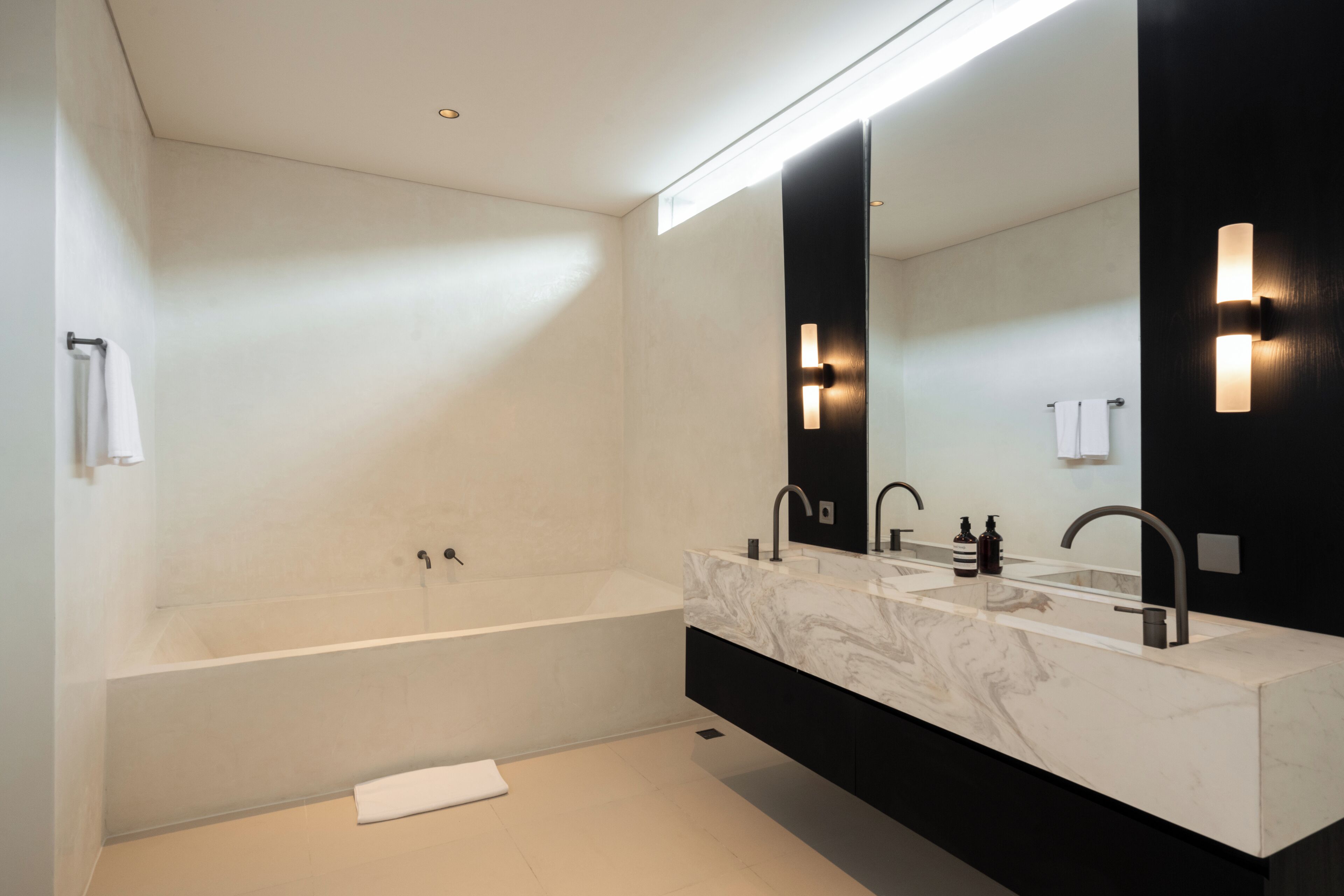 Un baño moderno con una bañera grande, un tocador doble y un espejo amplio.