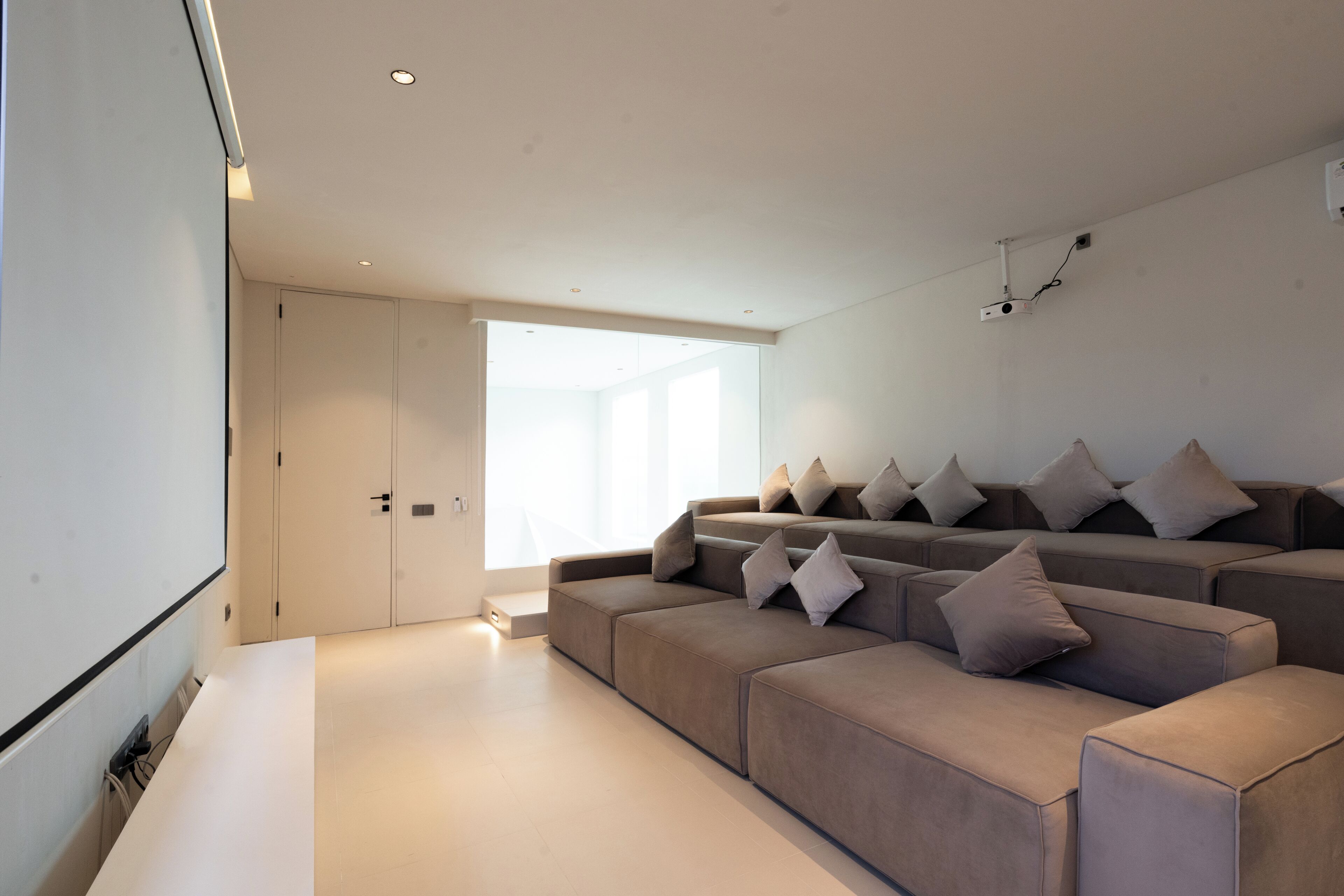 Una sala de estar moderna con un sofá modular grande, un televisor de pantalla plana y un ventanal que proporciona luz natural.