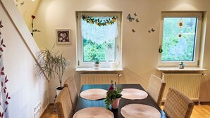 Ein Essbereich mit einem langen Tisch, vier Stühlen und einem Blumentopf.