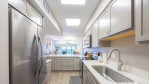 Une cuisine moderne dotée d’appareils électroménagers en acier inoxydable, d’un îlot central et offrant une vue sur l’espace de vie.