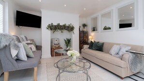 A living room with a grey sofa, beige sofa, and a glass coffee table. - Central Apartment with Patio - Sofa Bed (Cheltenham)