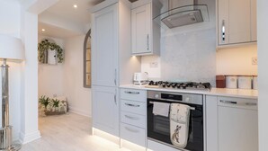 A modern kitchen with white cabinetry, a gas stove, an oven, and a dishwasher. - Central Apartment with Patio - Sofa Bed (Cheltenham)