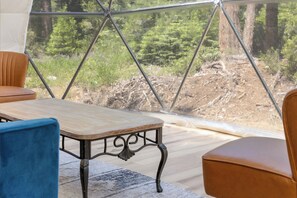Enjoy a serene forest view from the comfort of this room, featuring a wooden table and two chairs.