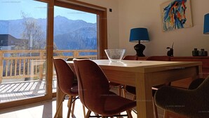 A dining area with a view of mountains, a table with chairs, and a painting on the wall. - Paradiski new, quiet and sunny Plan peisey (PEISEY-NANCROIX)