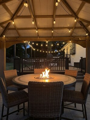 A covered outdoor patio with a central fire feature, wicker chairs, and string lights. - Dog Friendly - Central AC - Light Rail to Seattle (Bothell)