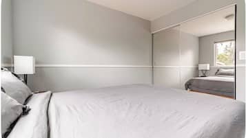 A bedroom with a bed, a bedside table, a lamp, and a large mirror.