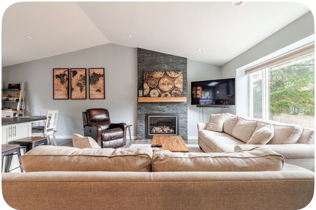 A modern living room with a fireplace, a leather armchair, a sofa, and artwork on the wall.