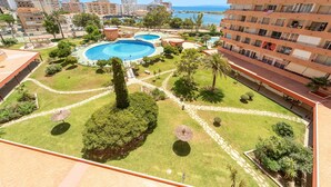 A resort with multiple swimming pools, a well-maintained garden, and a view of the sea. - WELCS ESTUDIO 213 EMP con piscina comunitaria (Rosas / Roses)