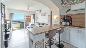 A modern kitchen with a wooden countertop, bar stools, and a view of the sea. - WELCS ESTUDIO 213 EMP con piscina comunitaria (Rosas / Roses)