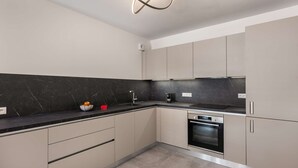 Et moderne køkken med en backsplash i sort marmor, rustfrie stålens hvidevarer og skabe i neutrale farver.