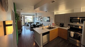 A modern kitchen with stainless steel appliances, a dining area with a glass table, and a view of a balcony. - Waterfront 2-bed/2bath Suite w/Indoor Pool & Hot Tub (Chelan)