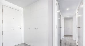 A corridor with white doors and a tiled floor.