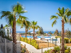 Un complexe hôtelier doté d’une piscine, de palmiers et offrant une vue sur la mer.