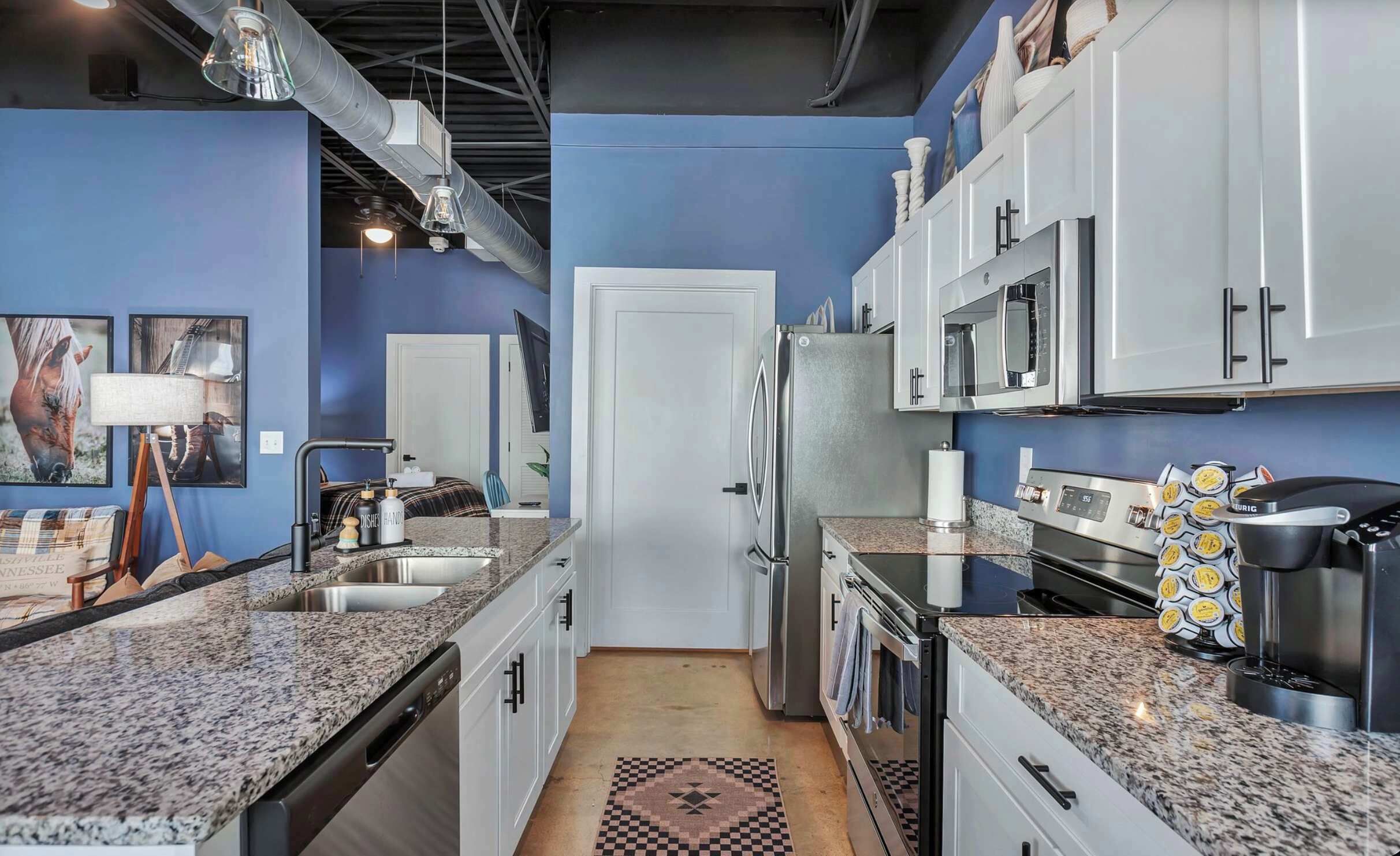 Una cocina moderna con encimeras de granito, electrodomésticos de acero inoxidable y una pared de acento azul.