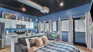 Une chambre moderne avec un grand lit, un coin cuisine et une vue sur la ville.