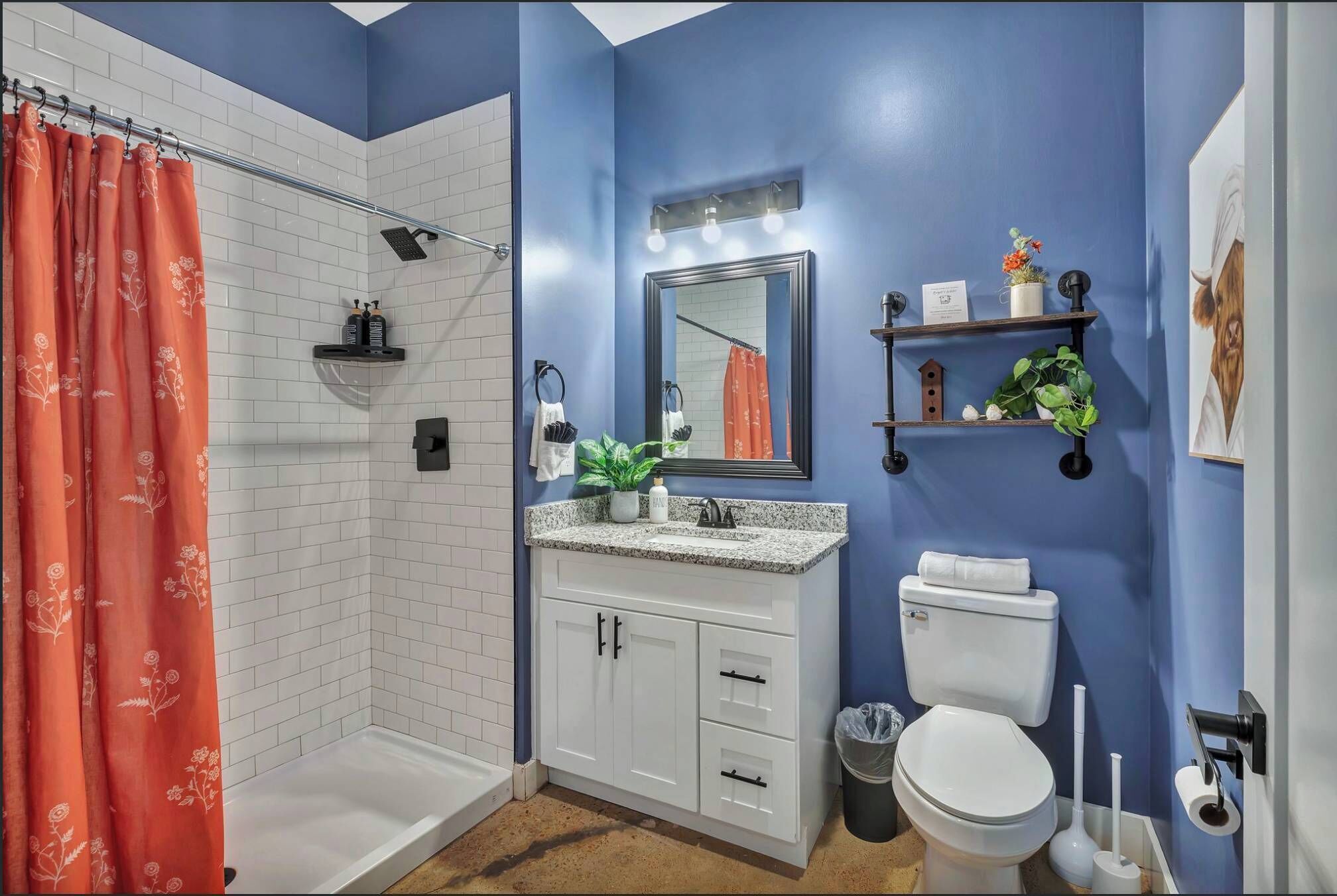 A bathroom with a shower, white cabinets, a sink, a toilet, and a mirror.