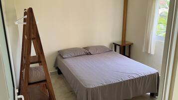 A bedroom with a bed, a wooden ladder, a nightstand, and a window with curtains.