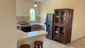 A kitchen with a gas stove, oven, refrigerator, wooden cabinet, and two bar stools. - Explore this spacious 3-bedroom apartment with WiFi, AC in nice Perula (Perula)