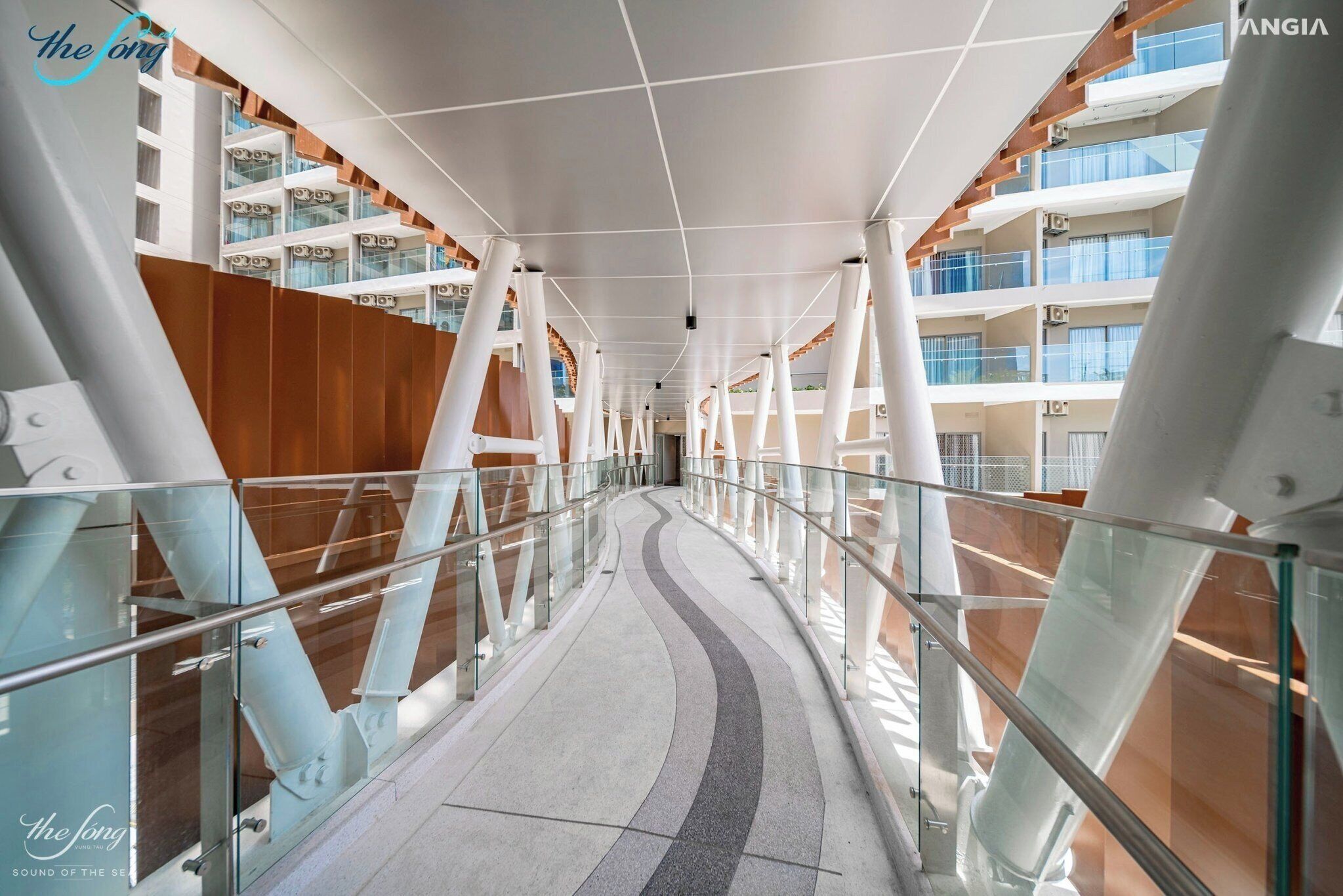 A modern corridor with glass railings and a curved ceiling, leading to multiple balconies.