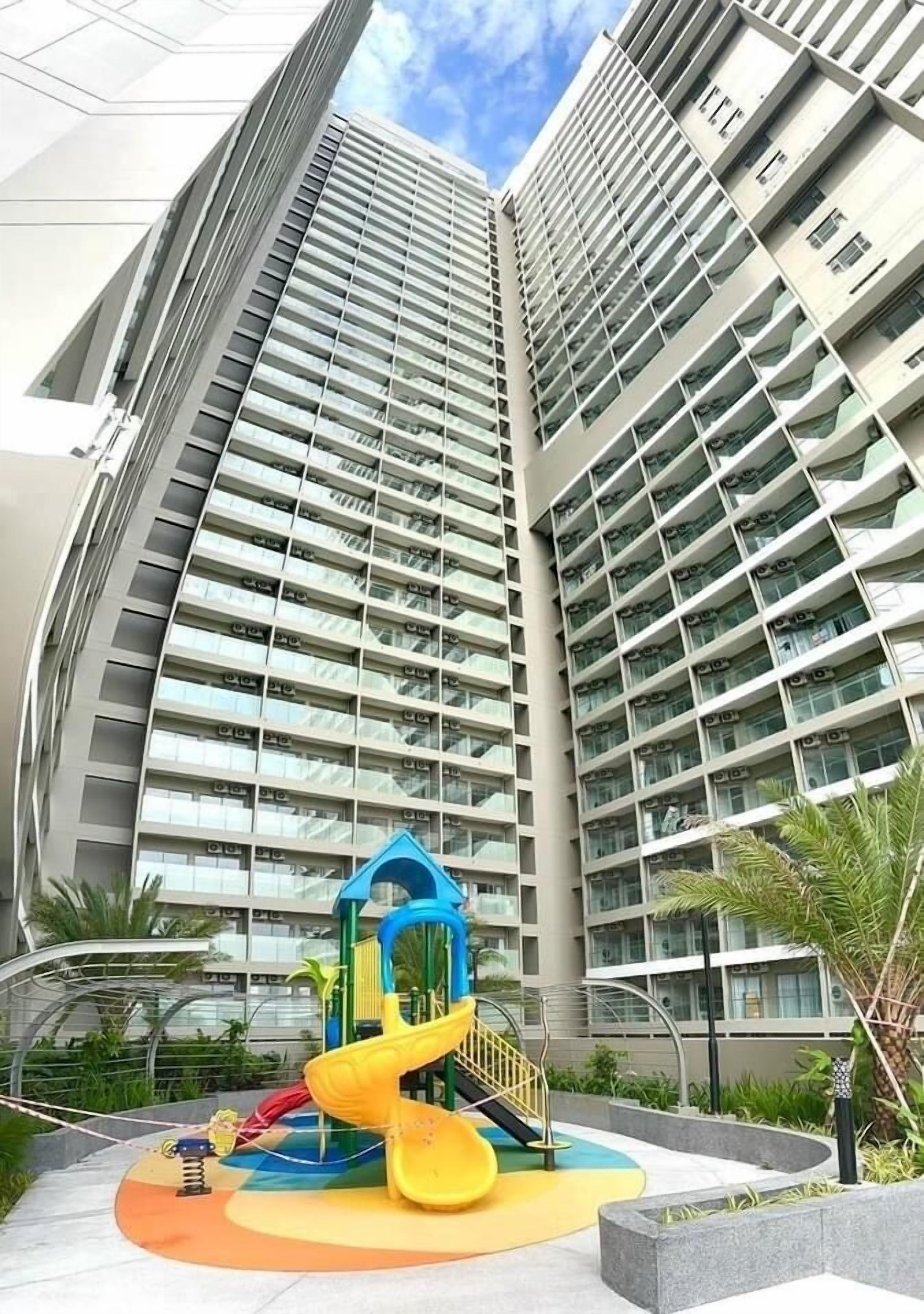 Ein Hochhaus mit einem Spielplatz, der eine gelbe Rutsche und eine Kletterkonstruktion zeigt.