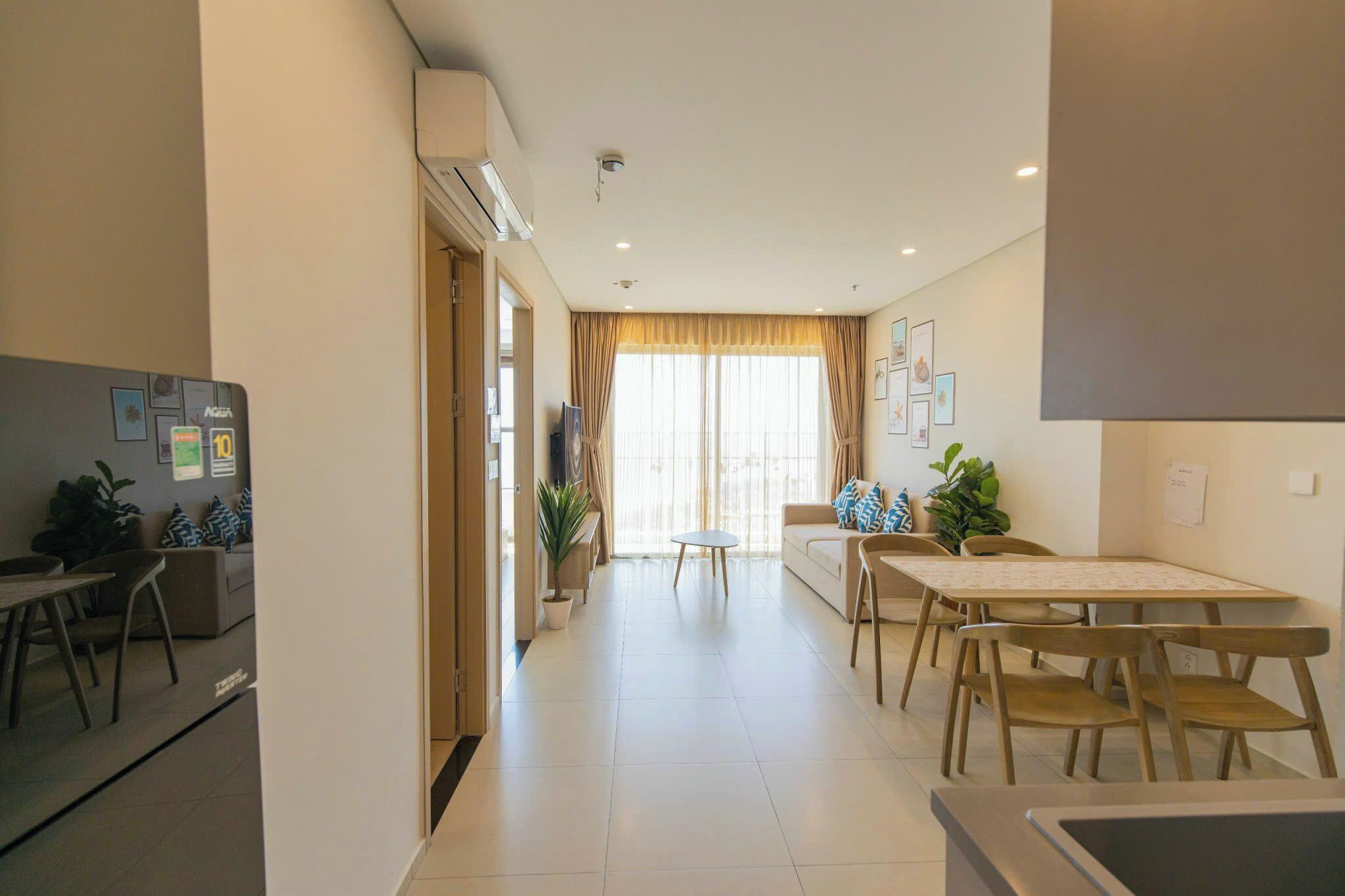 A modern hotel room with a dining area, a sofa, and a TV.