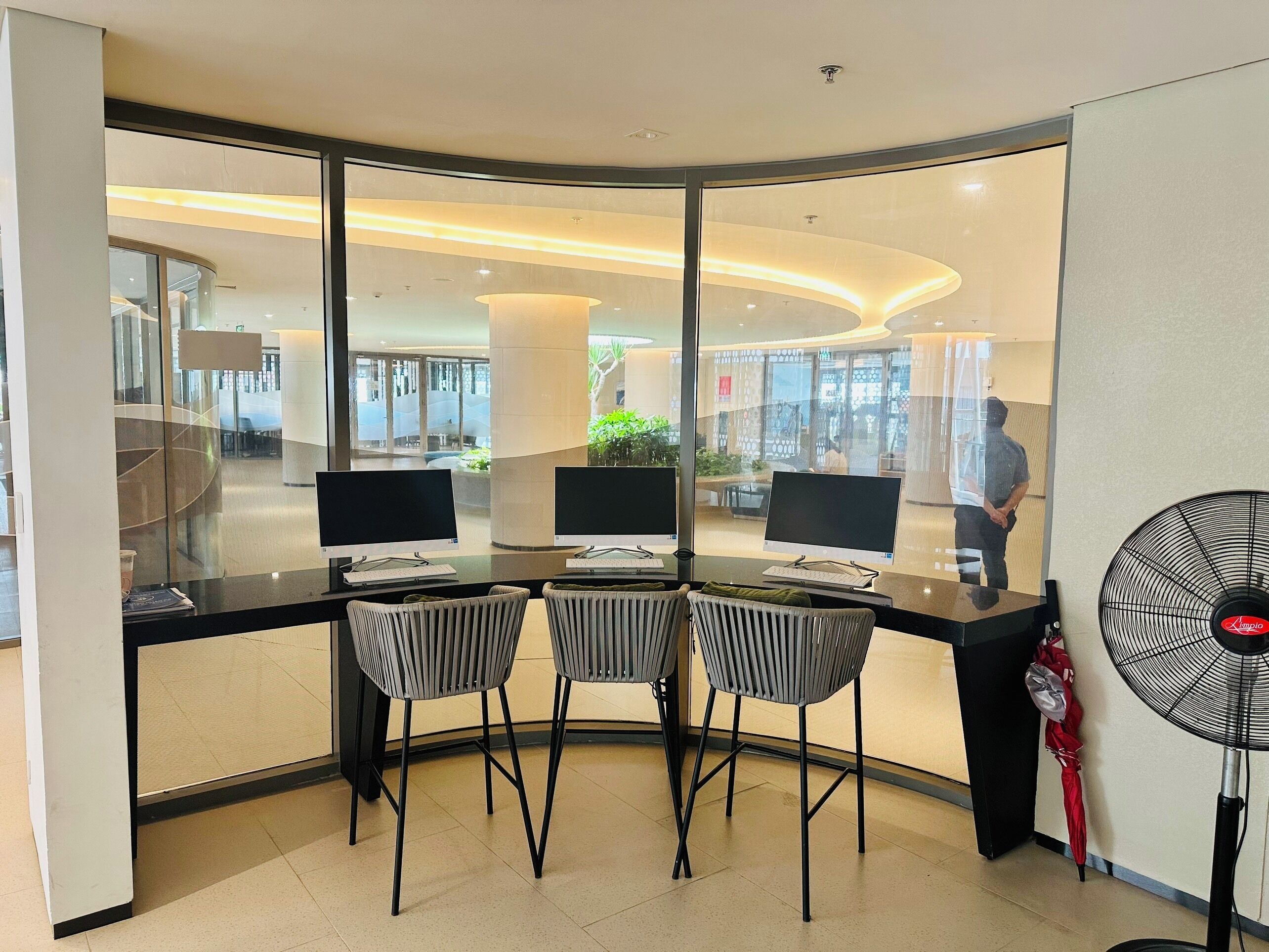 A modern office space with three desks, each with a computer and keyboard, and two chairs.