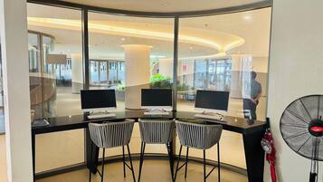 A modern office space with three desks, each with a computer and keyboard, and two chairs.